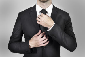businessman in black suit correcting his necktie