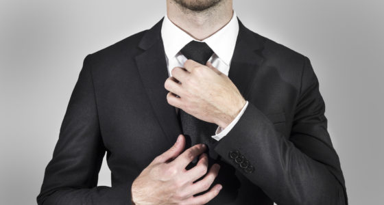 businessman in black suit correcting his necktie